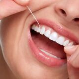 Beautiful young woman flossing white teeth. Dental health